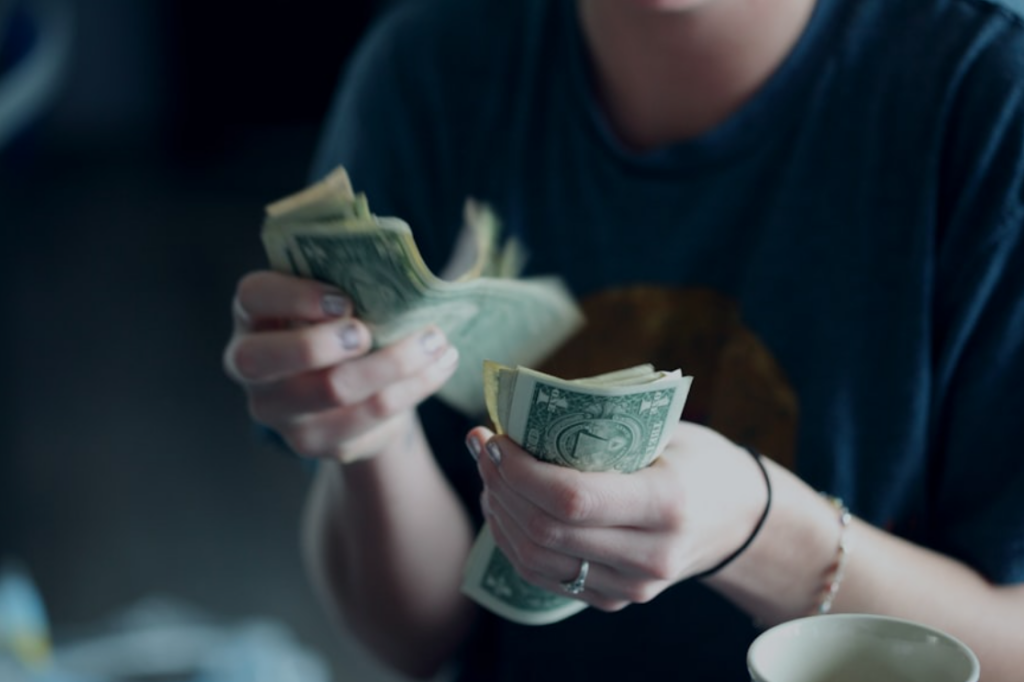 A close-up shot of a woman counting dollar banknotes