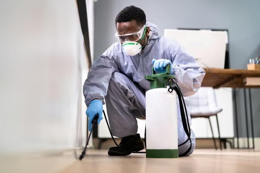 A pest control specialist using a spray can in a house.