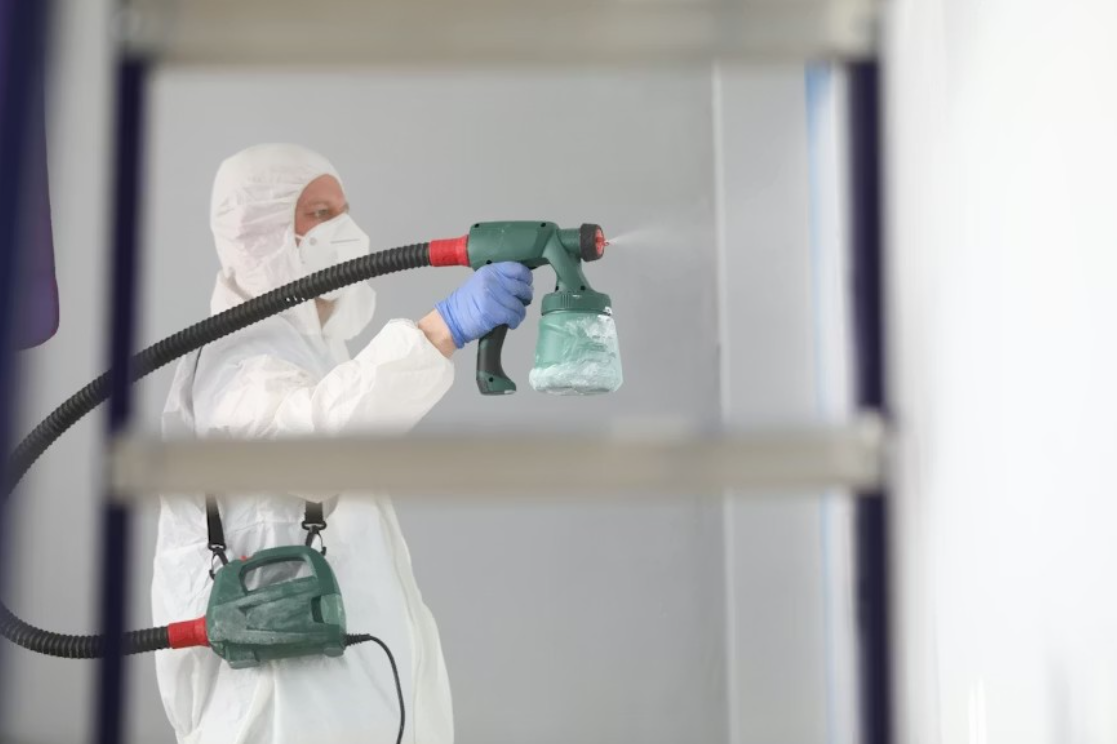 A pest control technician applying liquid chemical in a home.
