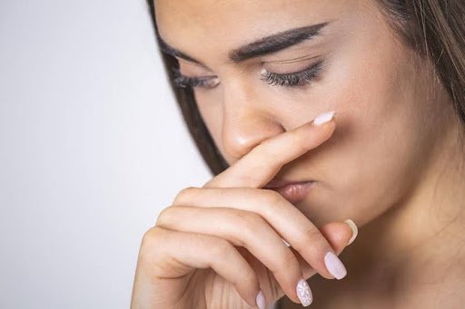 A woman covering her nostrils with her finger.