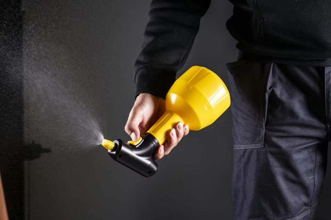 Close-up shot of a pest control professional holding a liquid pest control spray bottle.